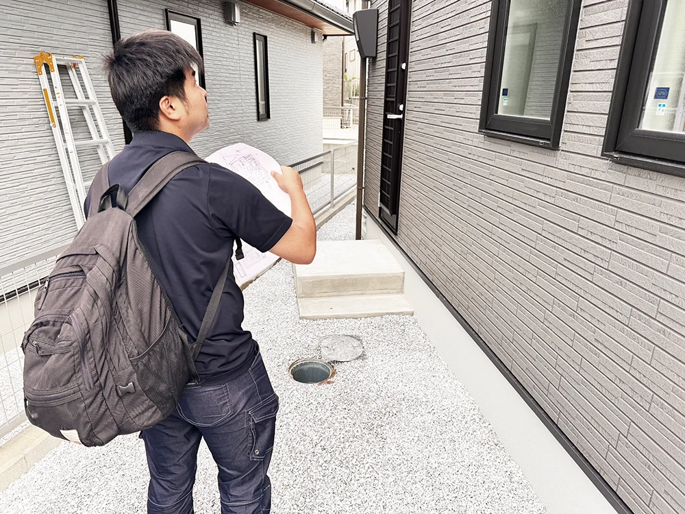 図面を手に建物まわりを確認する検査員