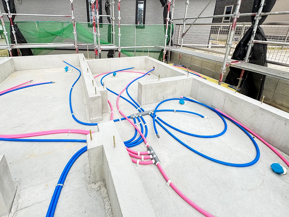 青とピンクの樹脂製給水管が敷設された基礎内部