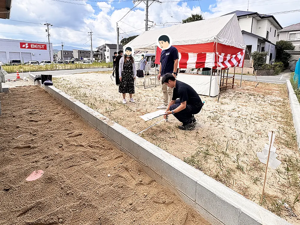 地縄が張られた敷地でスタッフが寸法を測り、建物の配置を確認する様子