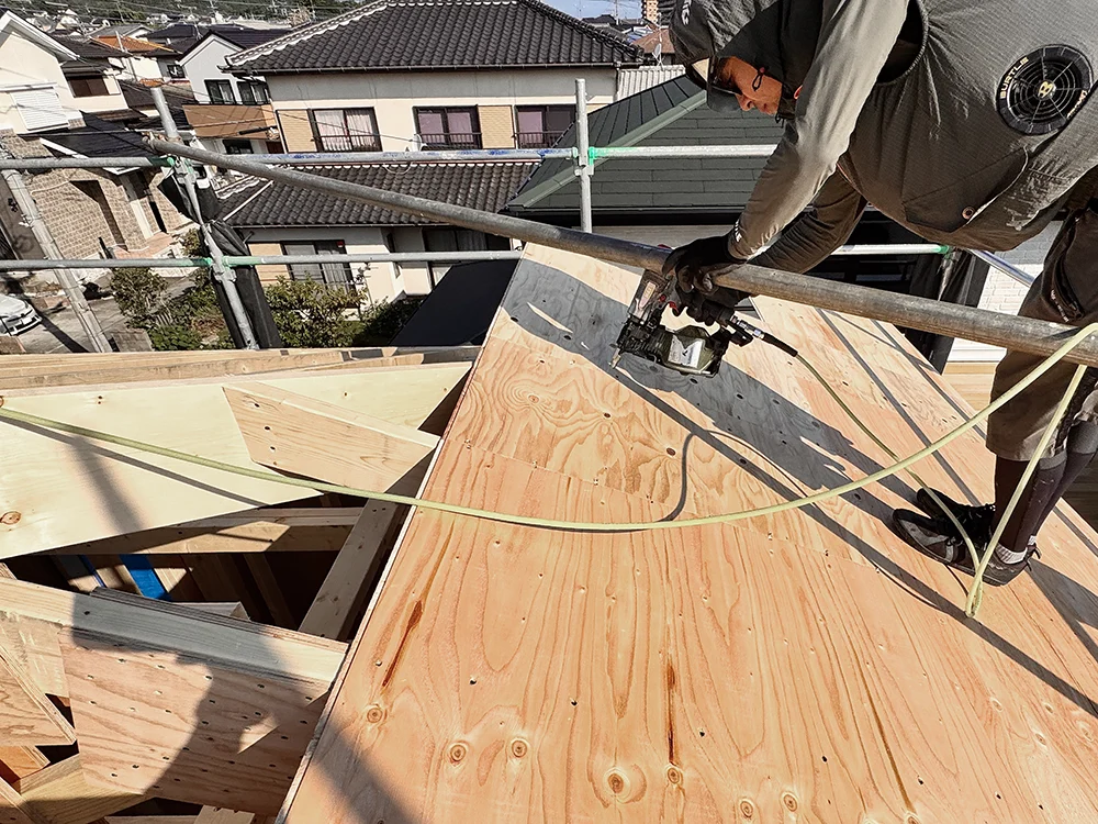 屋根下地の合板を釘打ちで固定する職人
