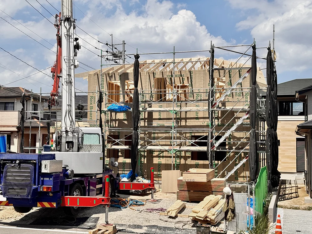 クレーン車で資材を上げ、2階部分まで組み上がった建物