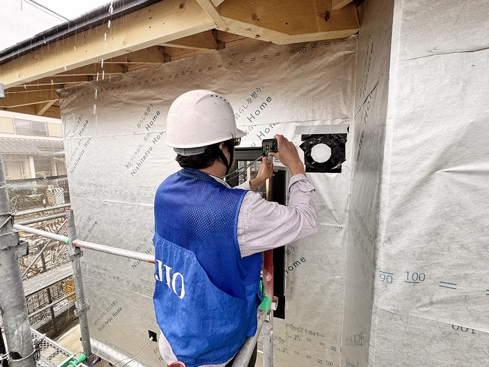 外壁の換気口まわりの下地を確認する検査員